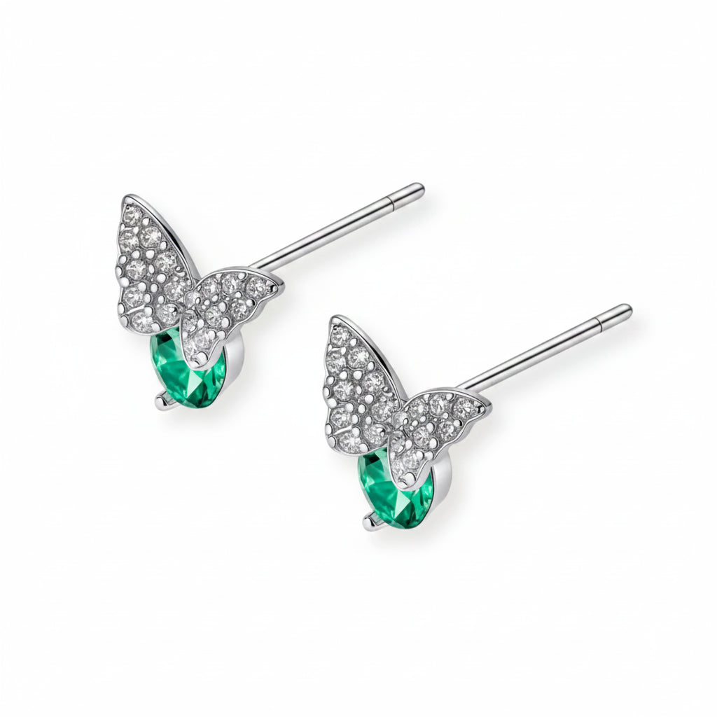Sterling silver butterfly stud earrings with crystal wings and mint green center stones on cream background.