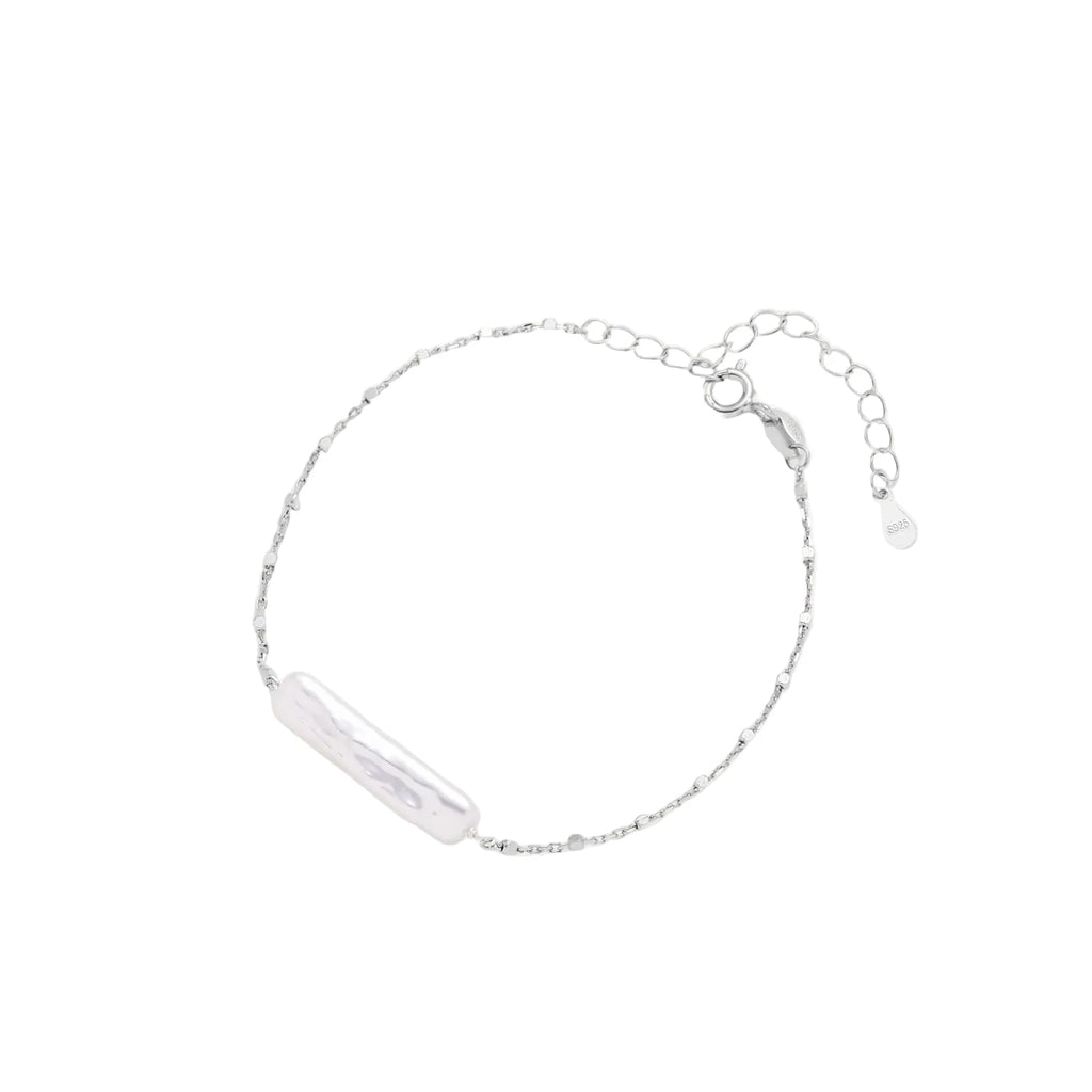 Minimalist bracelet with iridescent baroque pearl on rhodium-plated sterling silver chain against cream background