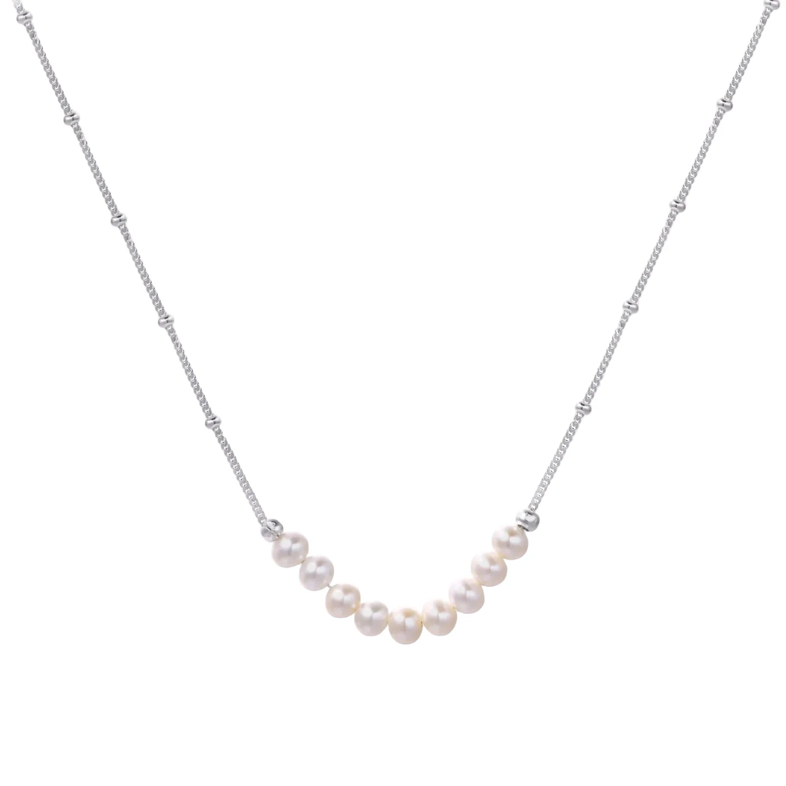 Delicate sterling silver chain necklace with small freshwater pearls arranged in a curved smile arc on cream background.