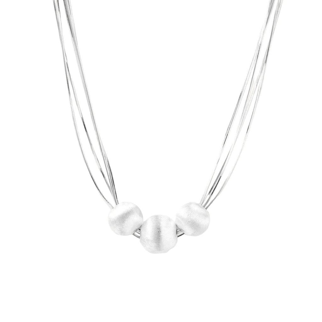 Sterling silver multi-strand necklace with three brushed round beads on cream background