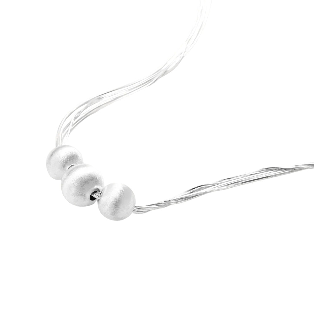 Sterling silver multi-strand necklace with three brushed round beads on cream background