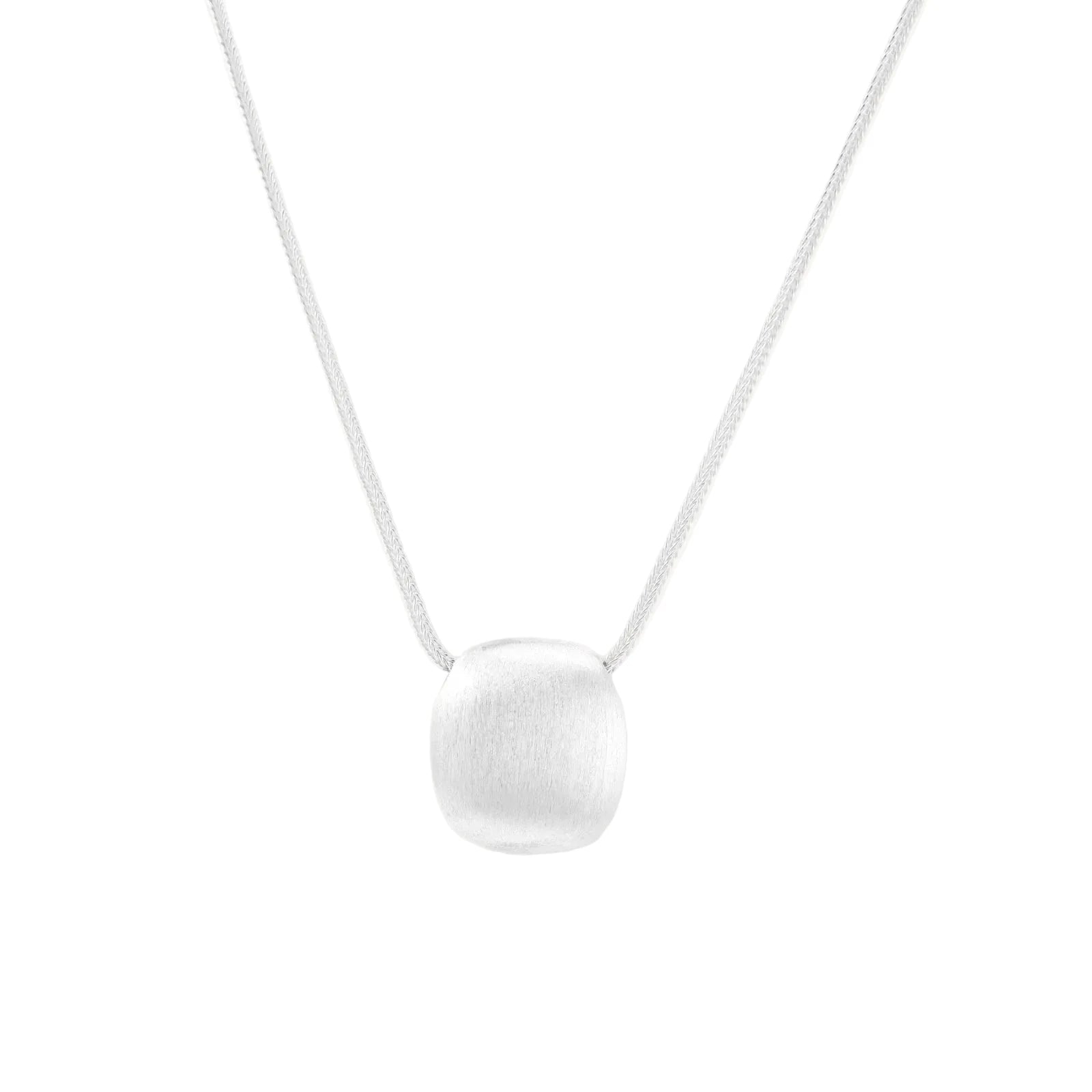 Minimalist brushed sterling silver dome pendant on delicate chain against cream background, showing matte textured finish
