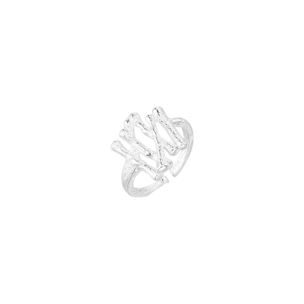 Sculptural sterling silver ring with organic branch design and textured surfaces on cream background