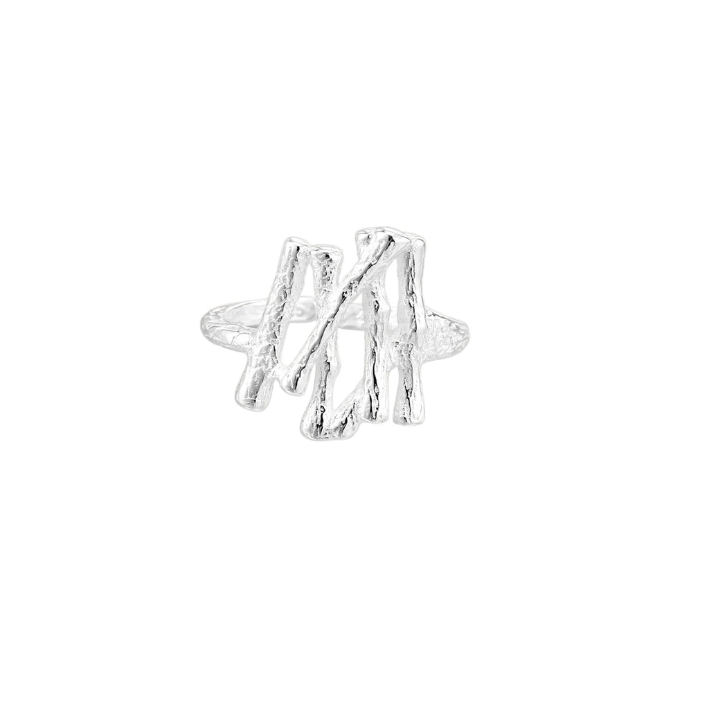 Sculptural sterling silver ring with organic branch design and textured surfaces on cream background